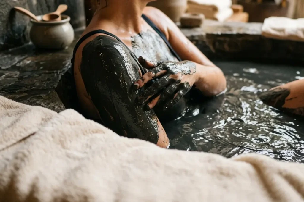 mud bath benefits shown as person soaks in mineral rich dark mud at spa treatment